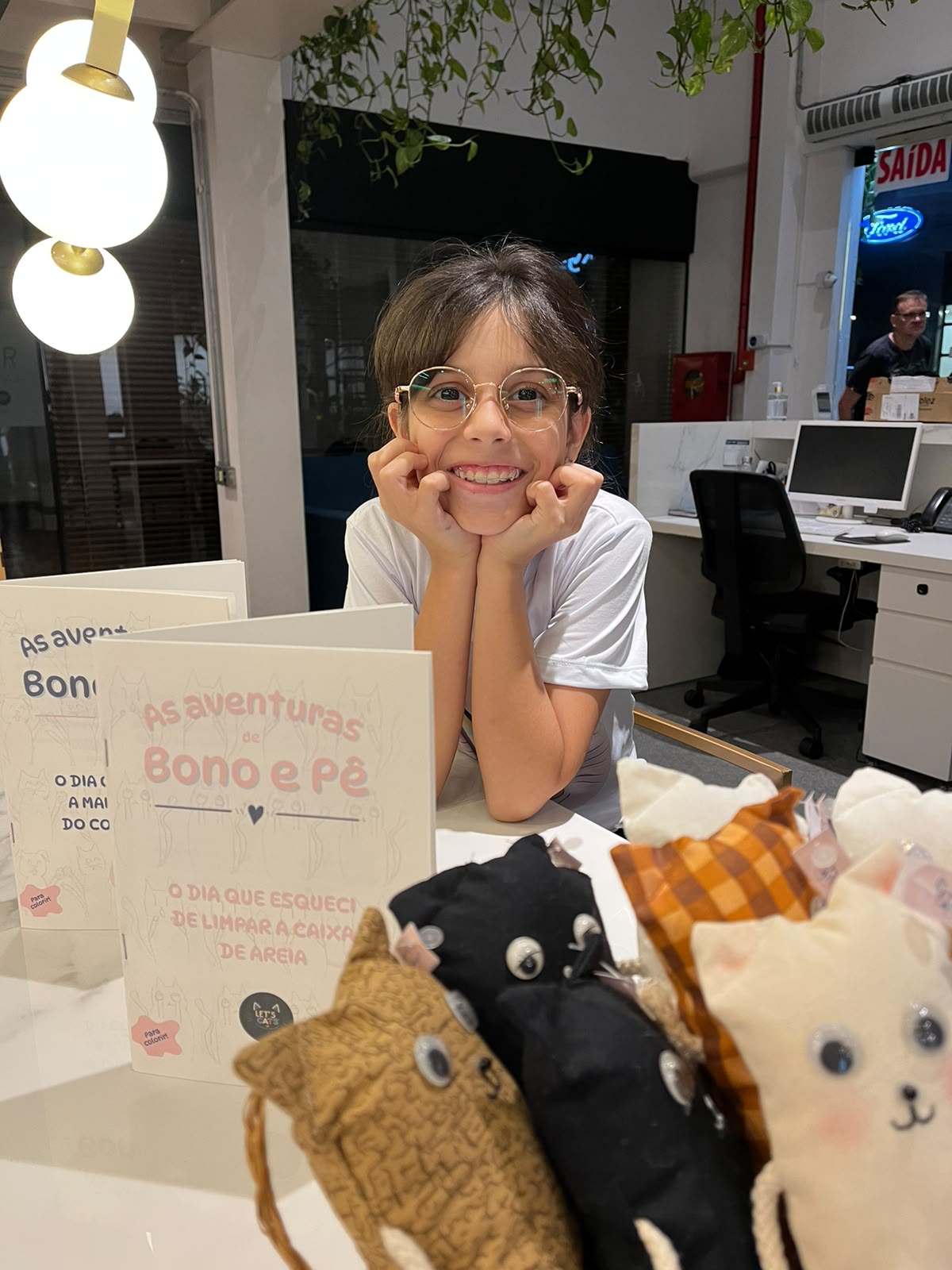 Sorriso da criadora da Let’s Cats junto aos livros e gatinhos da marca