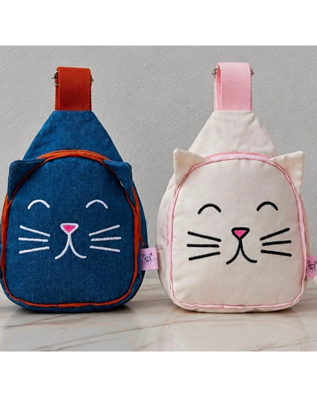 Mochilas Let’s Cats em denim azul e creme, com carinha de gato costurada
